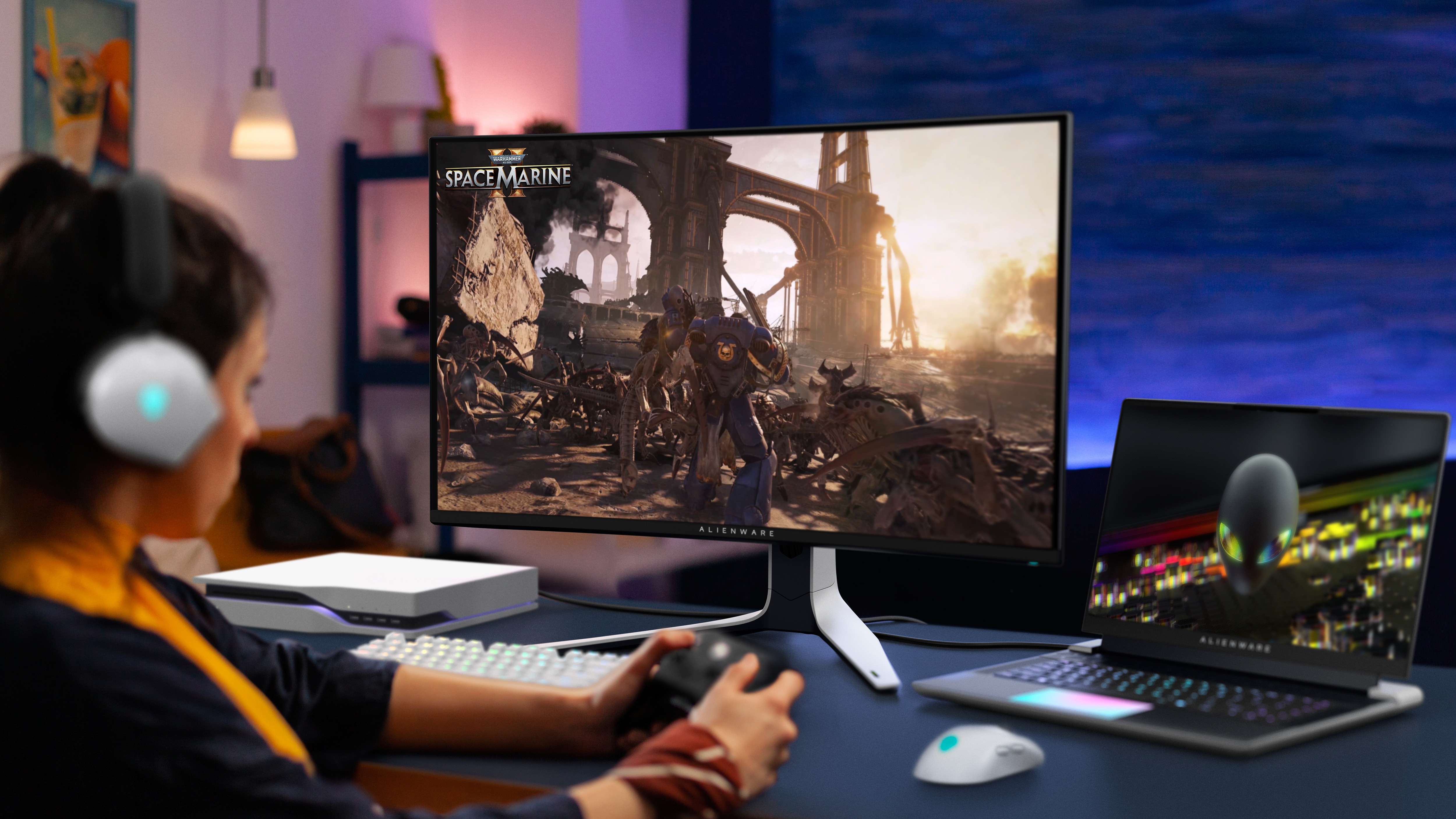 Kobieta grająca w Space Marine przy użyciu produktów Alienware na stole przed nią.