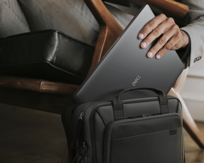 Zbliżenie dłoni wkładającej notebook Dell Pro 14 do torby.